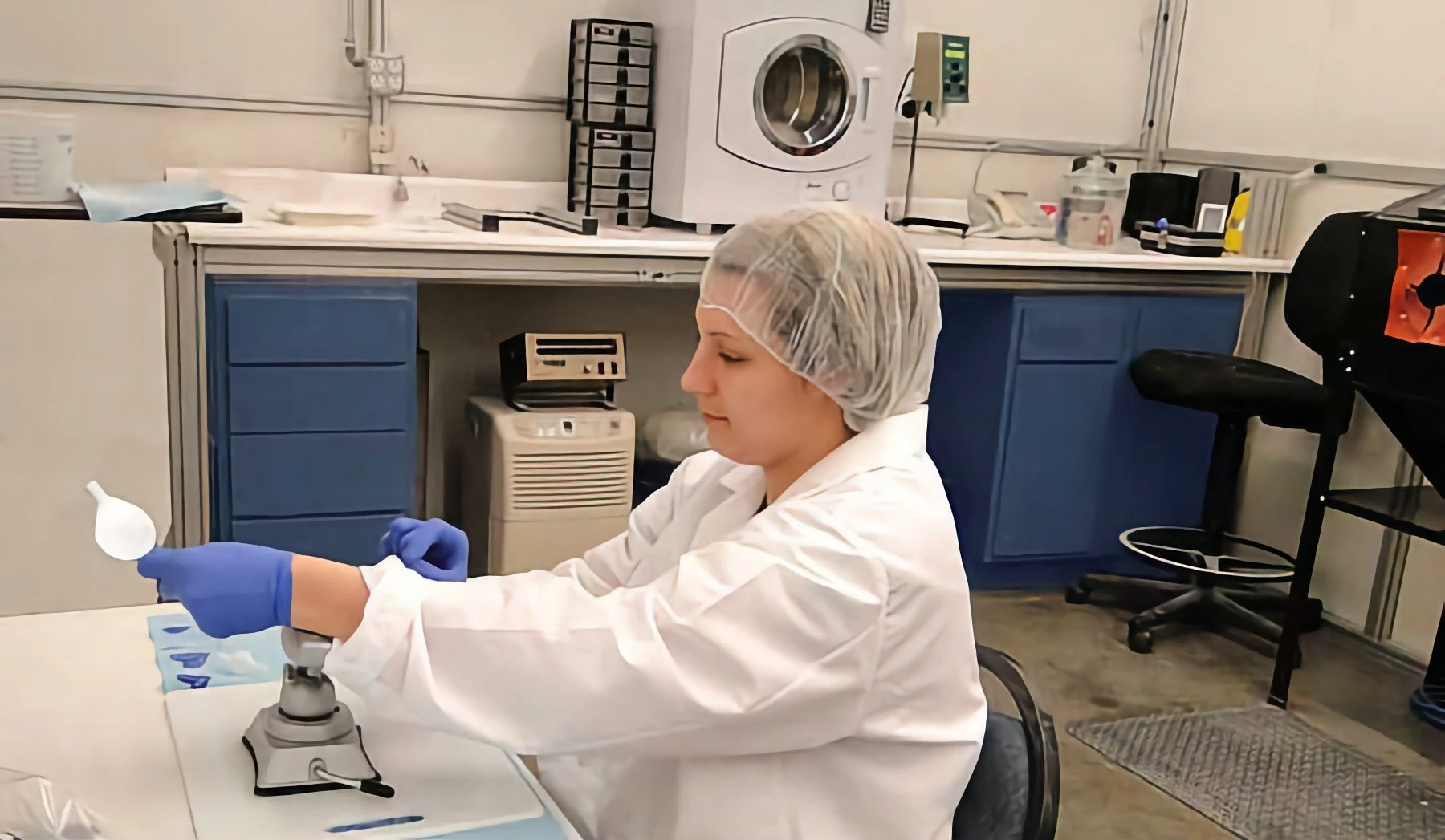 A woman in a white lab coat and blue gloves