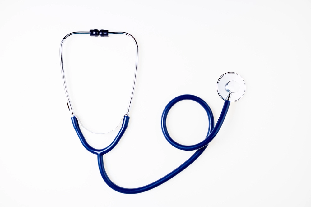 A blue stethoscope laying on top of a white surface