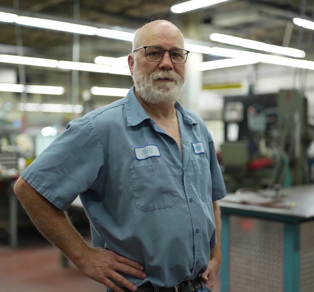 A man standing in a factory with his hands on his hips