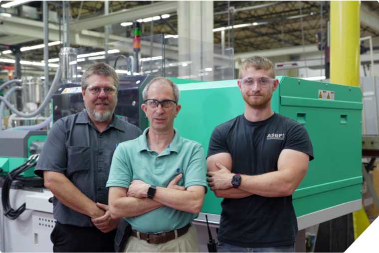 Three men standing in front of a machine in a factory